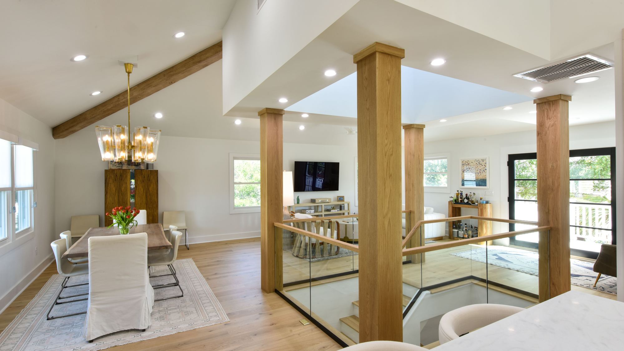 Vaulted dining room with white oak columns and brass chandelier