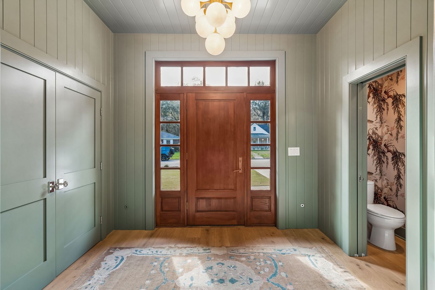 Sage green entry hall with wood door