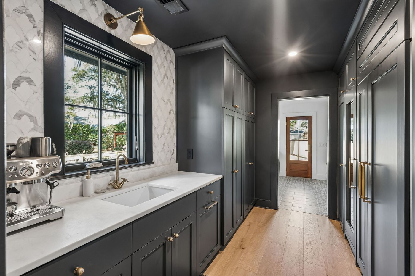 Pantry with scalloped marble tile and brass sconce